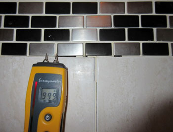 Moisture meter indicates elevated readings to bathtub / shower tile enclosure